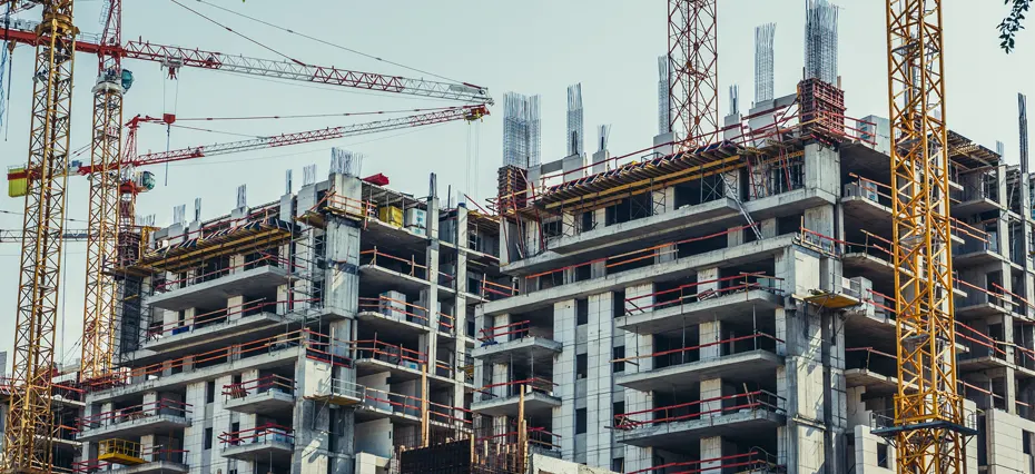 Imagem de prédio em execução com andaimes e guindastes, destacando o processo de prospecção de obras em construção.